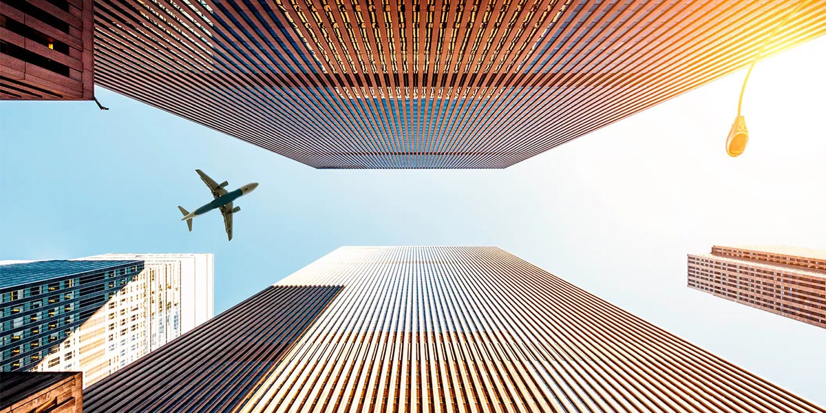 plane flying in between two skyscrapers
