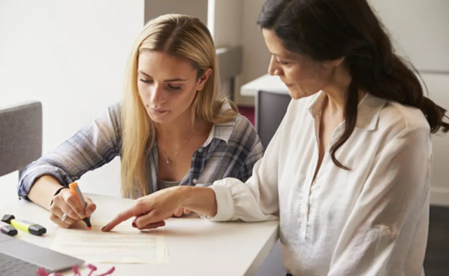 Woman writing in front of another woman