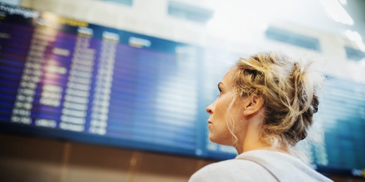 woman looking up at airport flight board