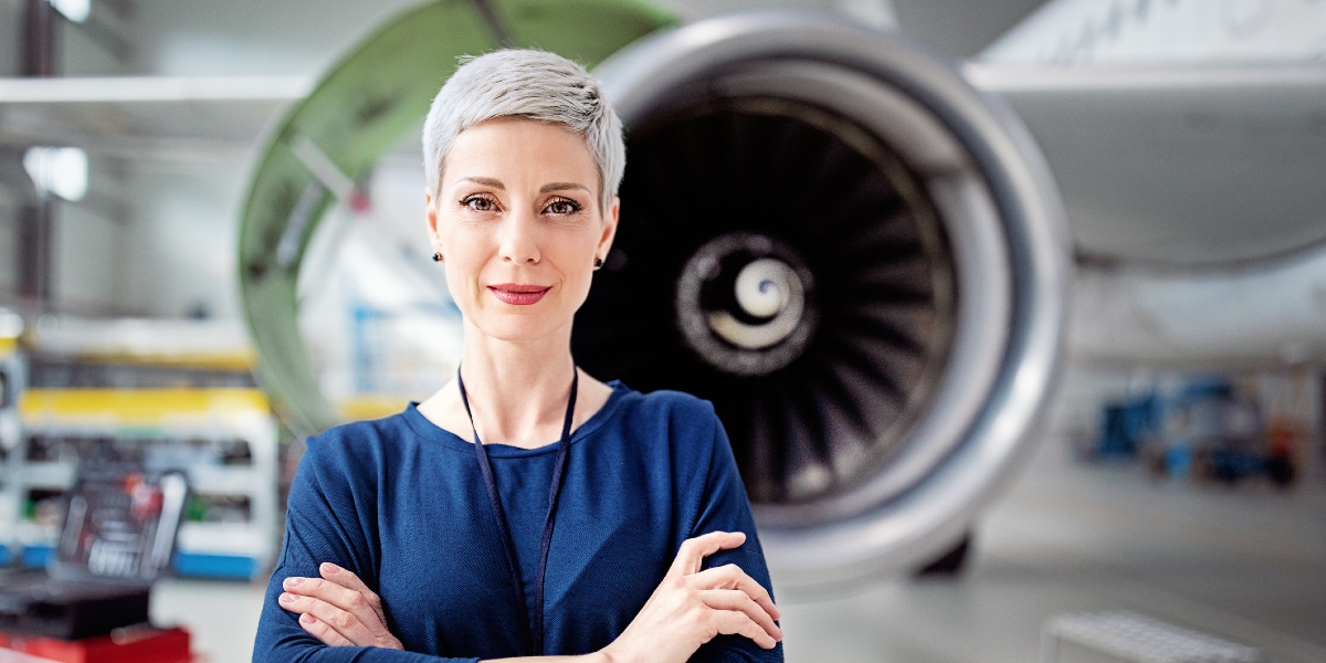 woman standing crossed arms in front of plane propeller