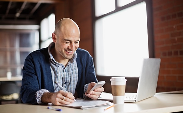 man working on laptop and phone