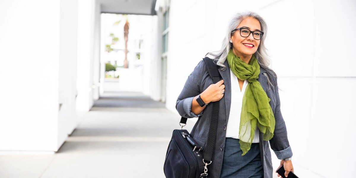 business woman walking with mobile device in hand