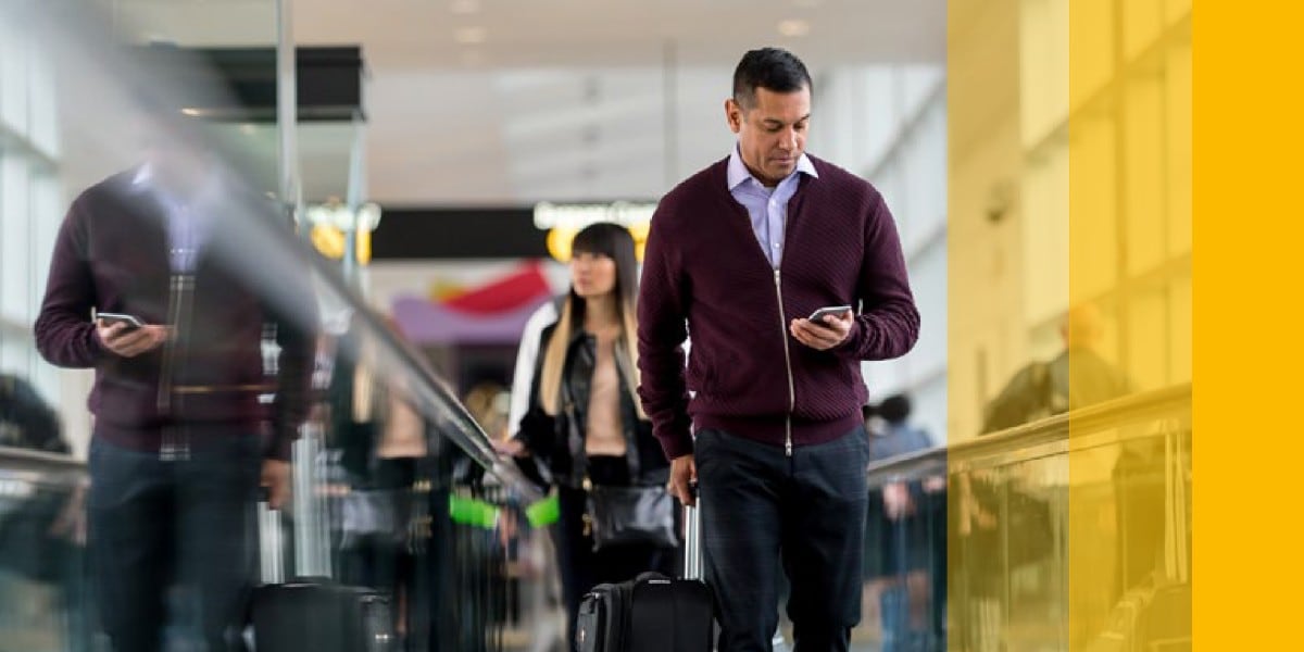 man walking on travellator lookikng down at mobile device