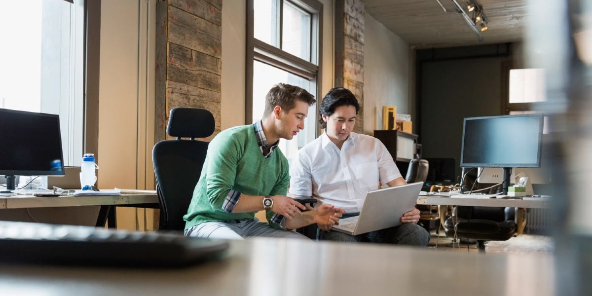 two men working on laptop together