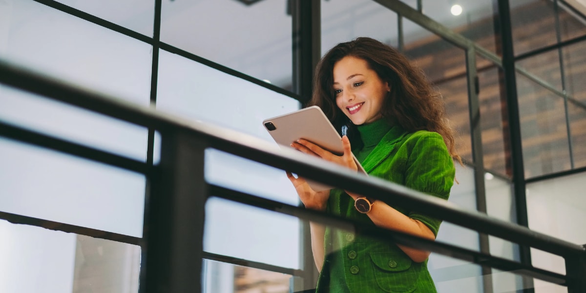 woman walking smiling and looking at a tablet