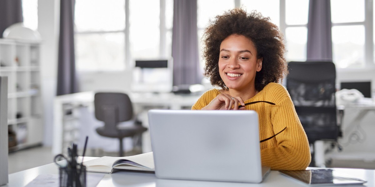 woman holding glasses working on laptop